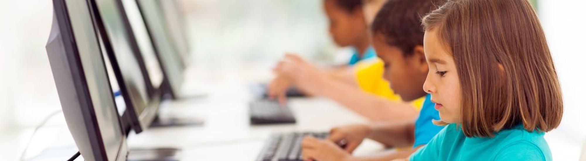 elementary aged students typing at computers 